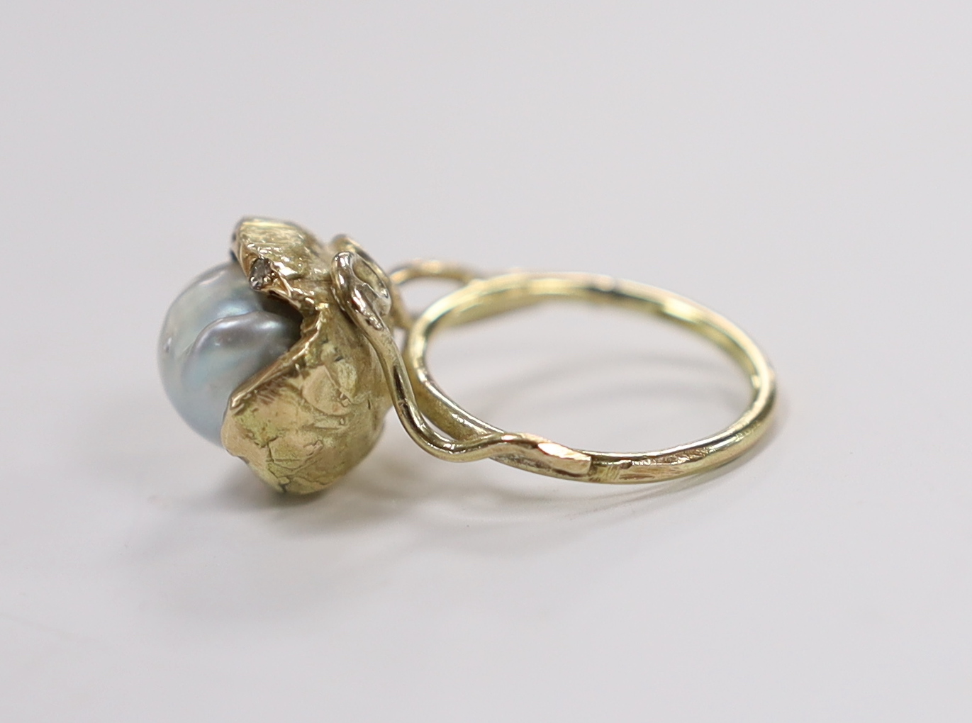 A yellow metal and baroque pearl set ring, with three stone diamond chip set setting, of foliate form, size K, gross weight 6.7 grams.
